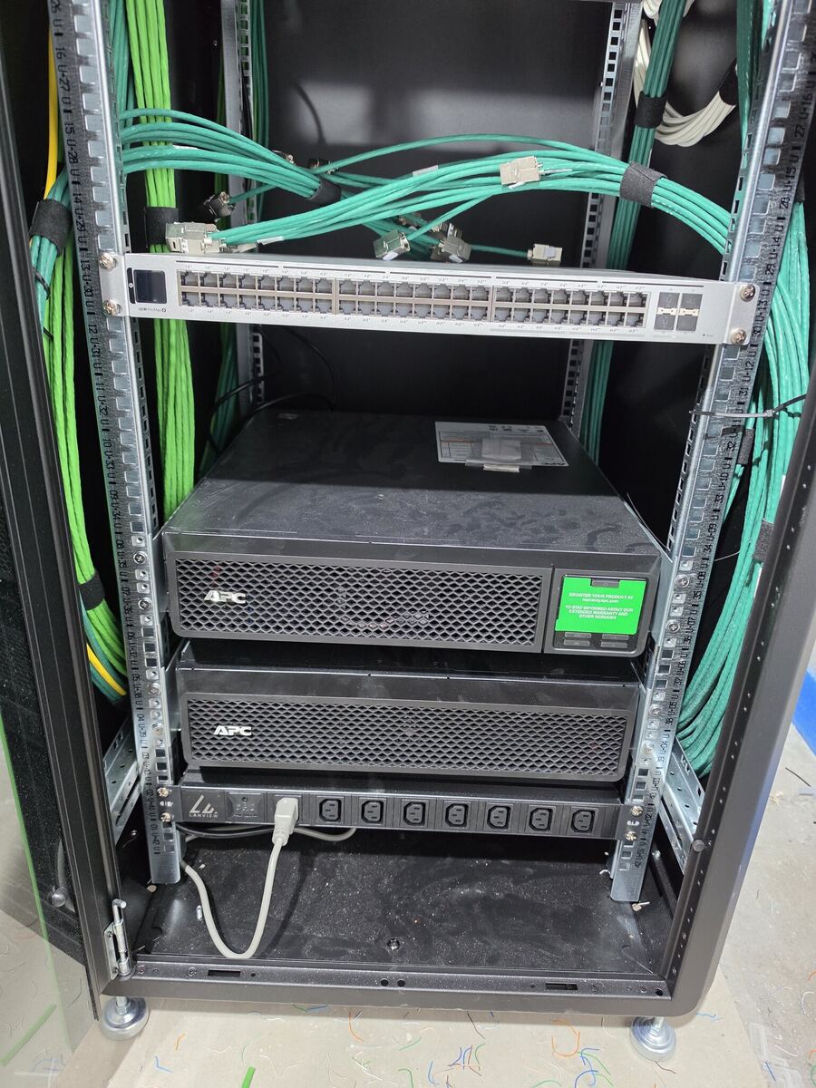 UniFi PoE-switch met UPS en netjes gelegde kabels in een netwerkkast